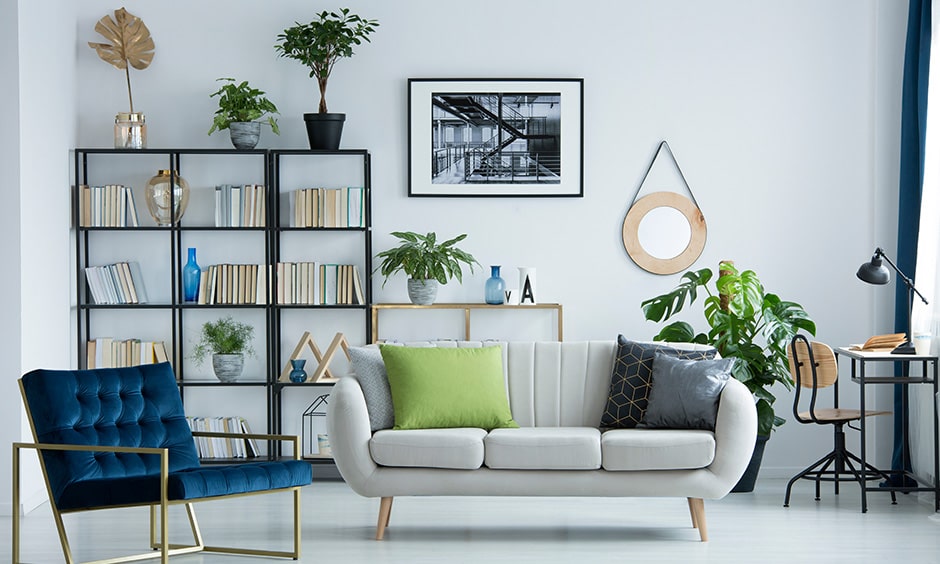 Home library idea in a white living room with corner library and a rich blue armchair