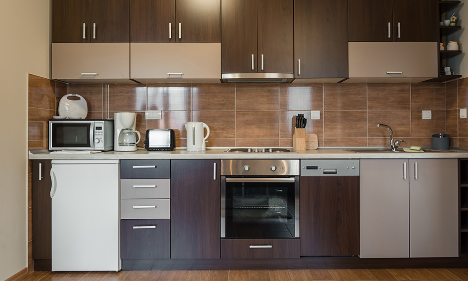 Shades of brilliant brown tiny one wall kitchen have space for a mini-fridge and cabinets to store crockery.