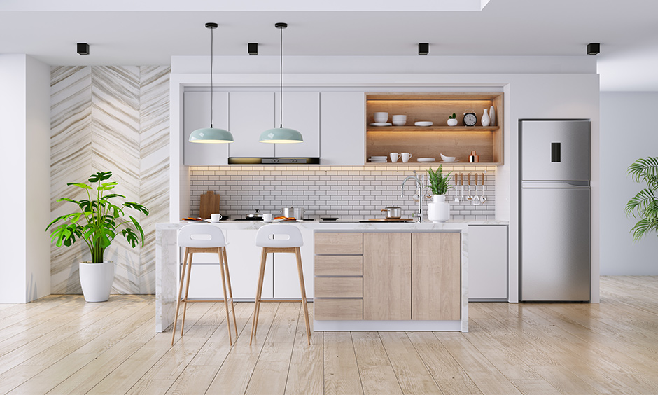 White & woody one wall kitchen with island, brick backsplash, cabinets & pair of pendant light looks elegant.
