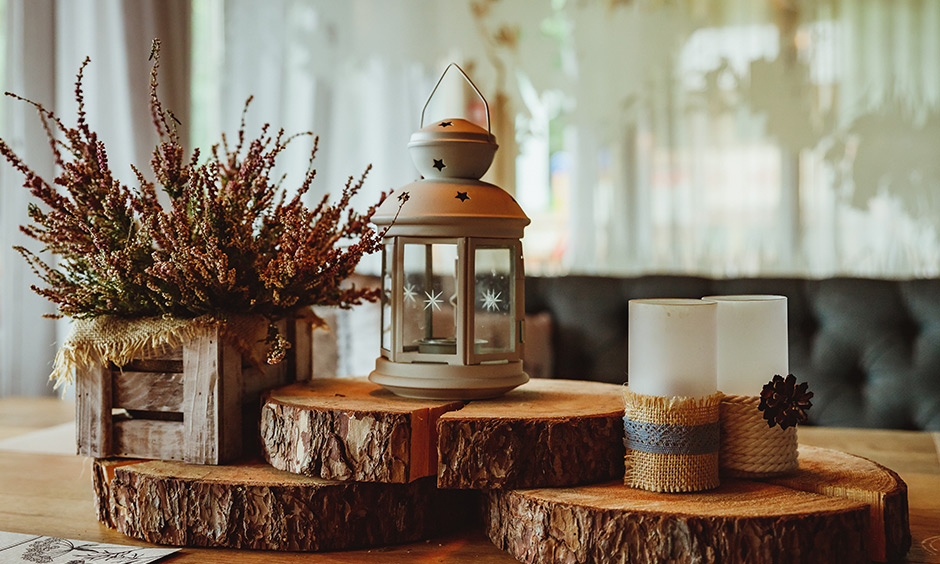 Farmhouse modern decor with candles, wooden discs, lanterns, dried tree branches & pendant light brings rustic feel.