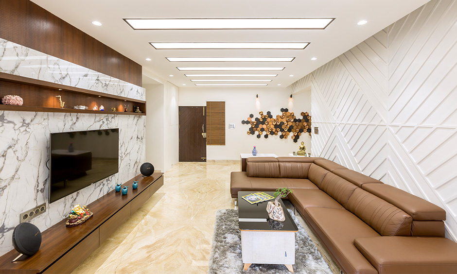 Uber-modern living room in white and brown colour theme has minimalist tv unit designed by interior firms in Bangalore.