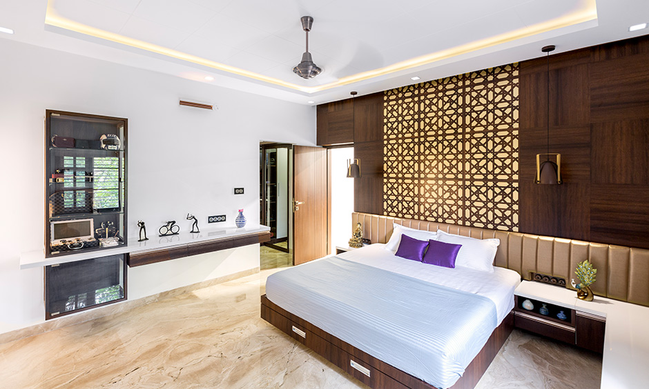 Master bedroom designed with a back panel in a jaali pattern and spotlights by interior design firms in Bangalore.