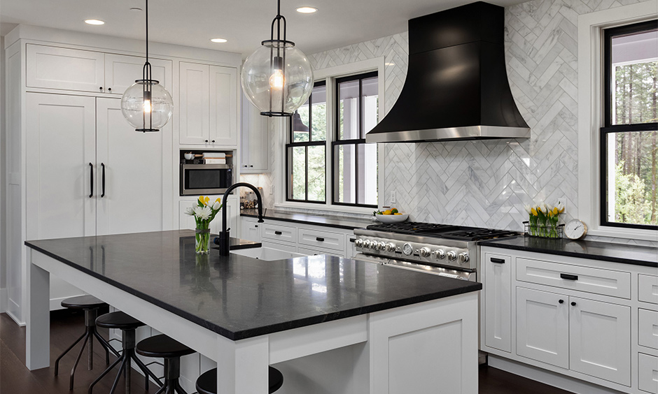 White island kitchen has Ubatuba black granite countertops with white cabinets that look aesthetic.