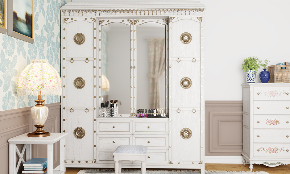 The old white wardrobe/almirah  decorated with vintage doorknobs look beautiful in the bedroom.