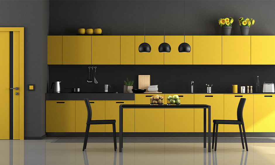 The yellow and black modular kitchen cum dining area has a black dining table that brings in fresh bursts of colour.