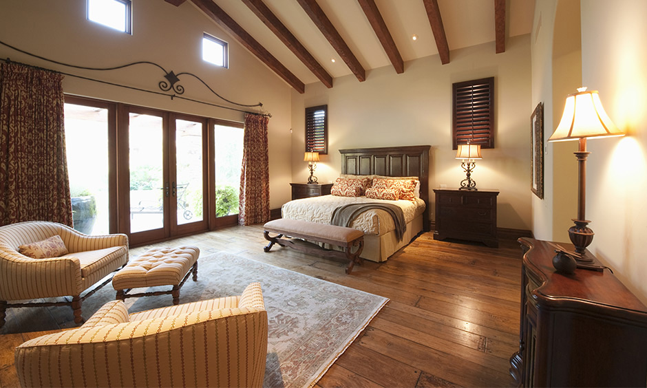 An ornate bedroom carpet design in off-white against wooden flooring creates a striking contrast