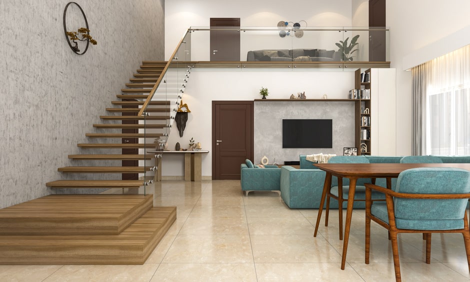 A floating stair with glass railings is in an open layout of living and dining areas