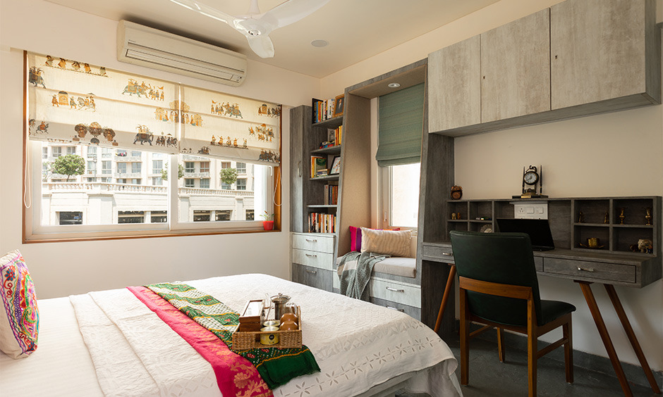 Small bedroom with bookshelves and an attached study table, designed to maximise space