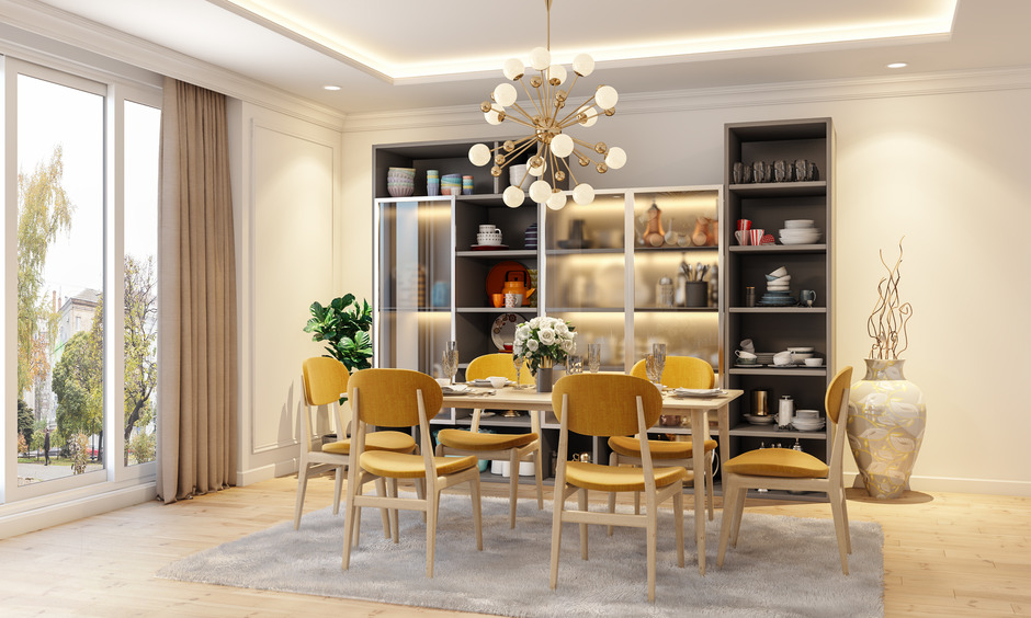 A Sputnik chandelier, stylish chairs, a sleek cabinet, and flower vases enhance a warm dining room in a 5 bhk house.
