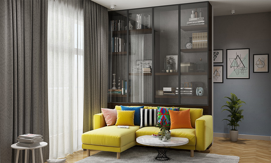 Floor-to-ceiling glass almirah with adjustable shelves for a modern living room display.