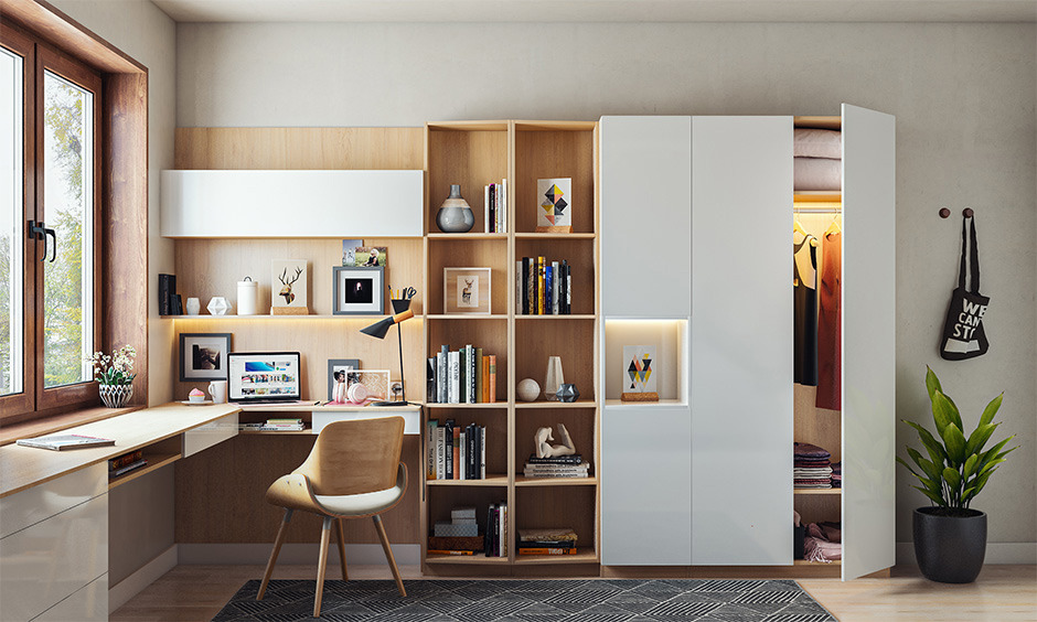 L-shaped home office desk with built-in bookshelf by a large window, offering ample natural light and storage space.