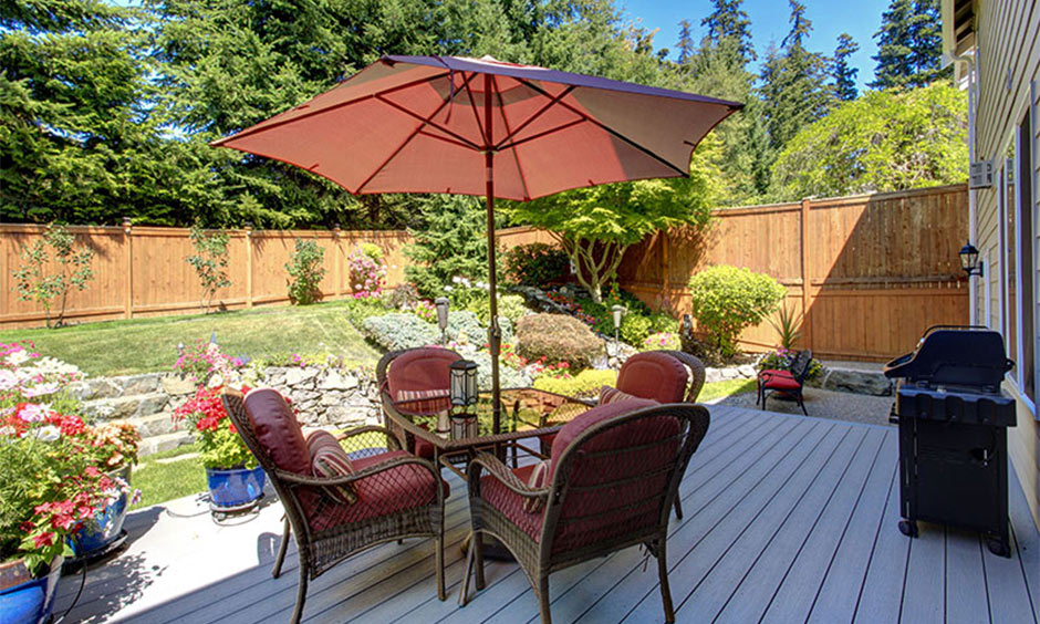 Outdoor deck with wicker chairs, umbrella, and greenery, creating a cafe-like vibe at home.