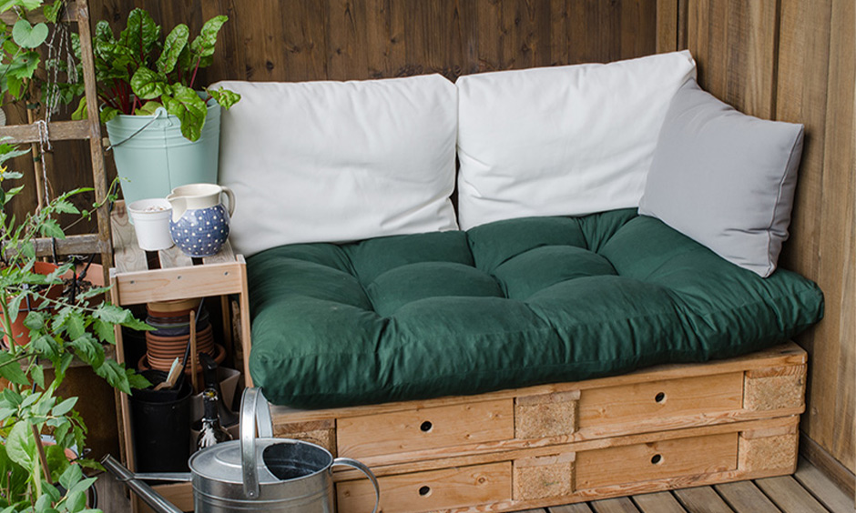 Rustic pallet lounge seat with cushions and potted plants, perfect for a cosy balcony retreat.