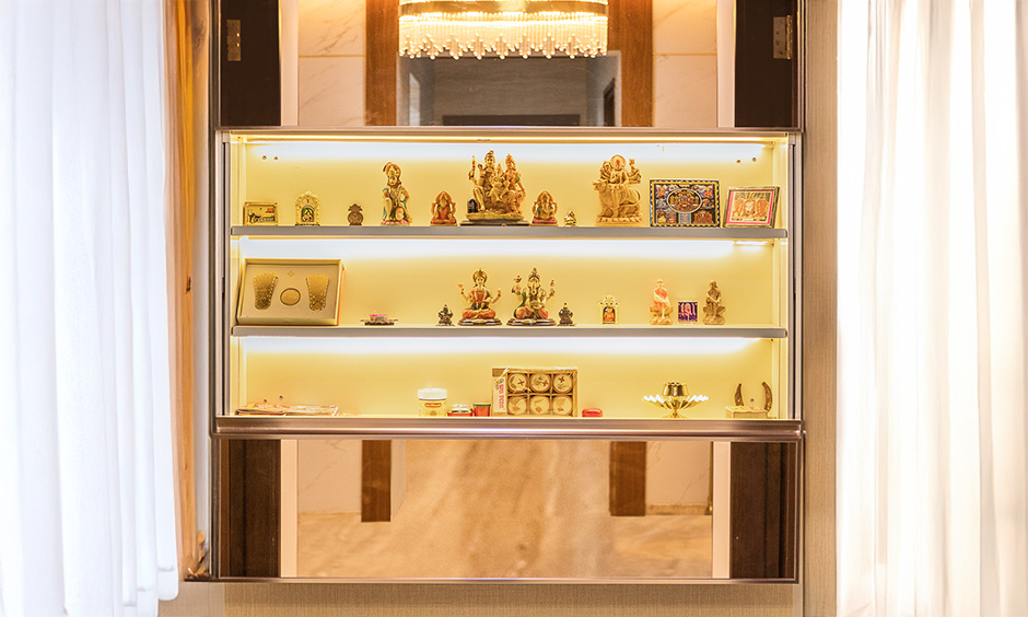 Luxury pooja room with mirror-panelled shutters on the pooja unit, reflecting light and space.